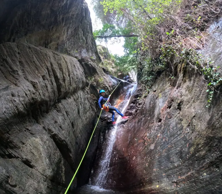 Una noia baixant en ràpel per una paret vertical de roca al primer ràpel de la part avançada del barranc d'Estaron.