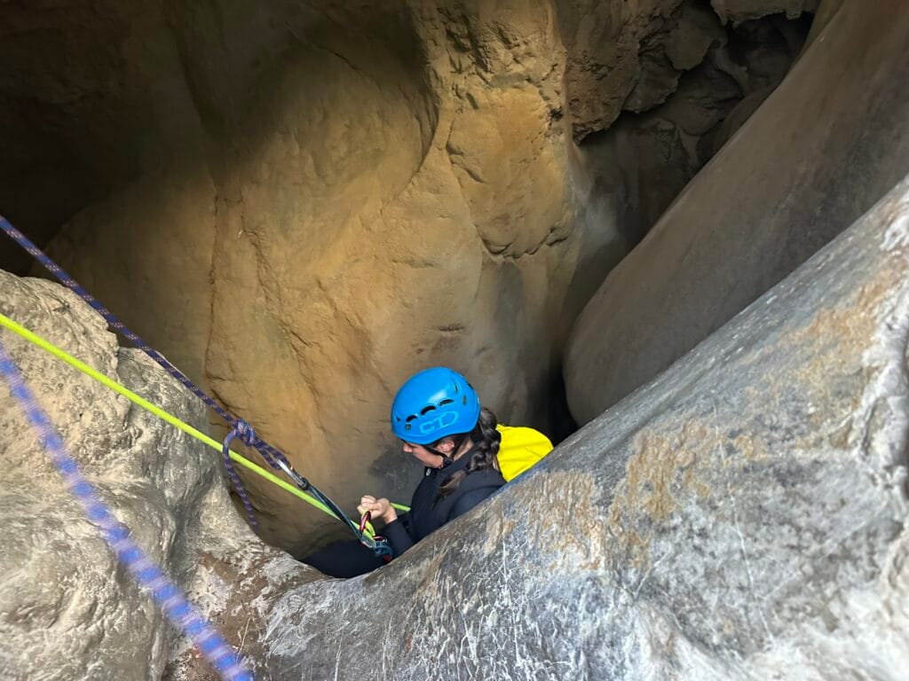 Una noia baixant amb corda pel ràpel de 20 metres que entra a la majestuosa cova del barranc de l'Infern, a Collegats.