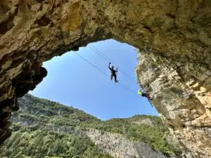 Excursionista creuant el pont tibetà més impressionant del pallars Jussà , a la Via Ferrada Paret de les Arcades amb el pantà de Terradets de fons.
