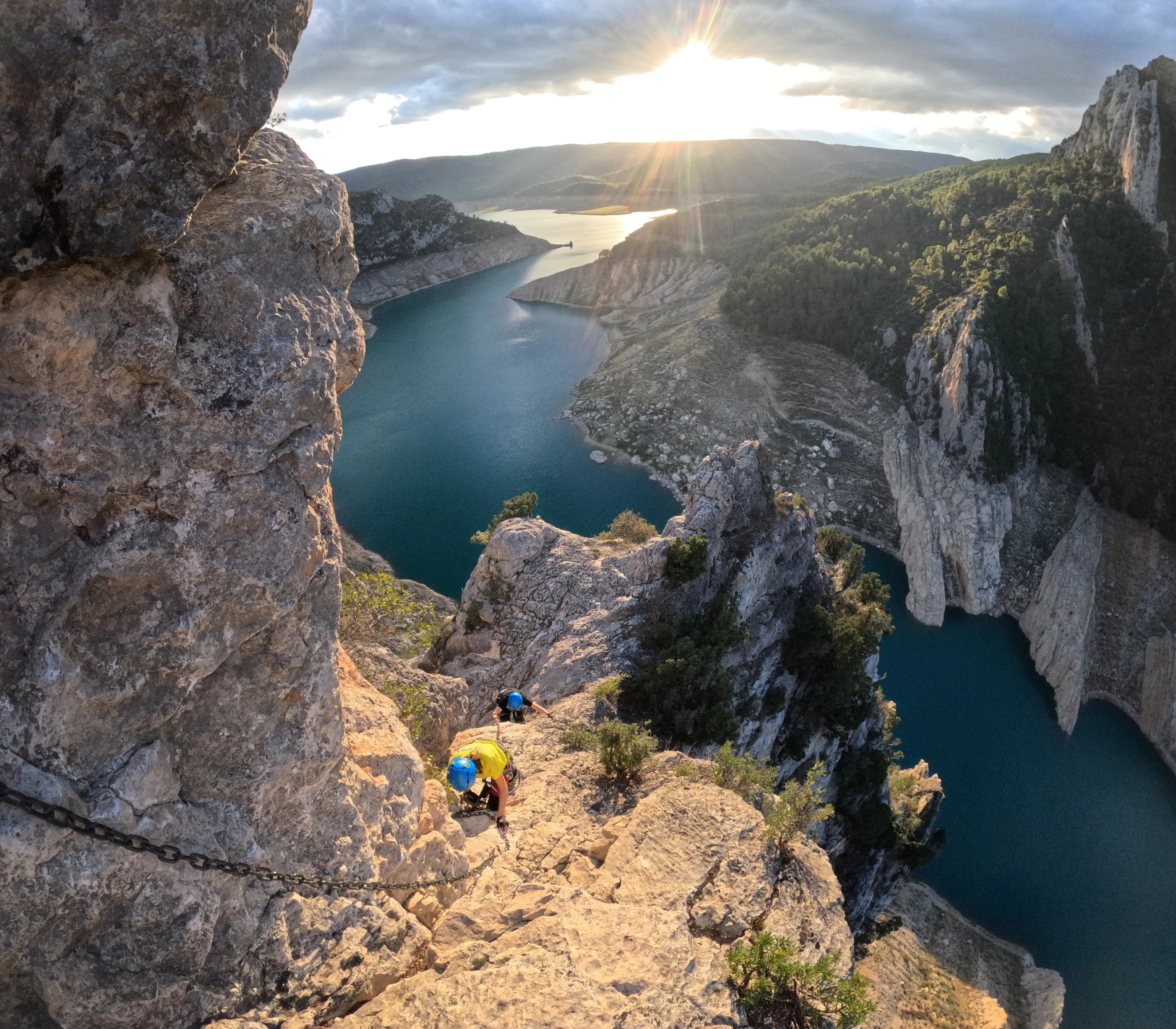 Dues noies progressant per la via ferrada Teletubbies i Olmo Soler a Àger, amb les aigües blaves del pantà de Canelles al fons.
