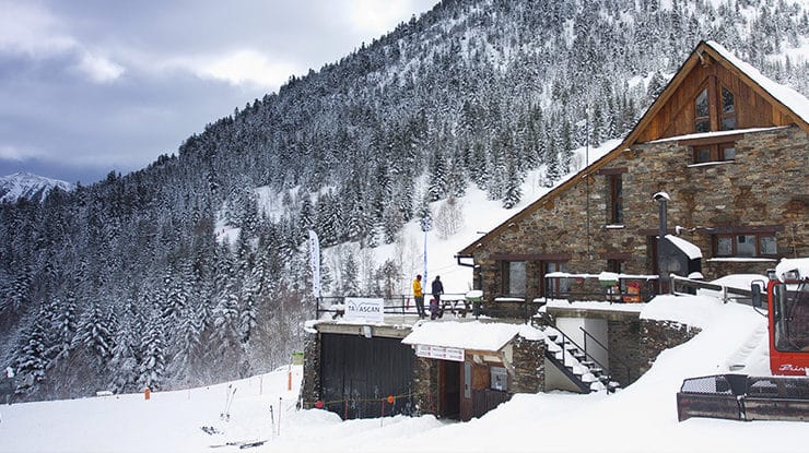 El refugio de la Pleta del Prat en Tavascan bajo un cielo cubierto, rodeado de bosque de pino negro y montañas del Pallars Sobirà.