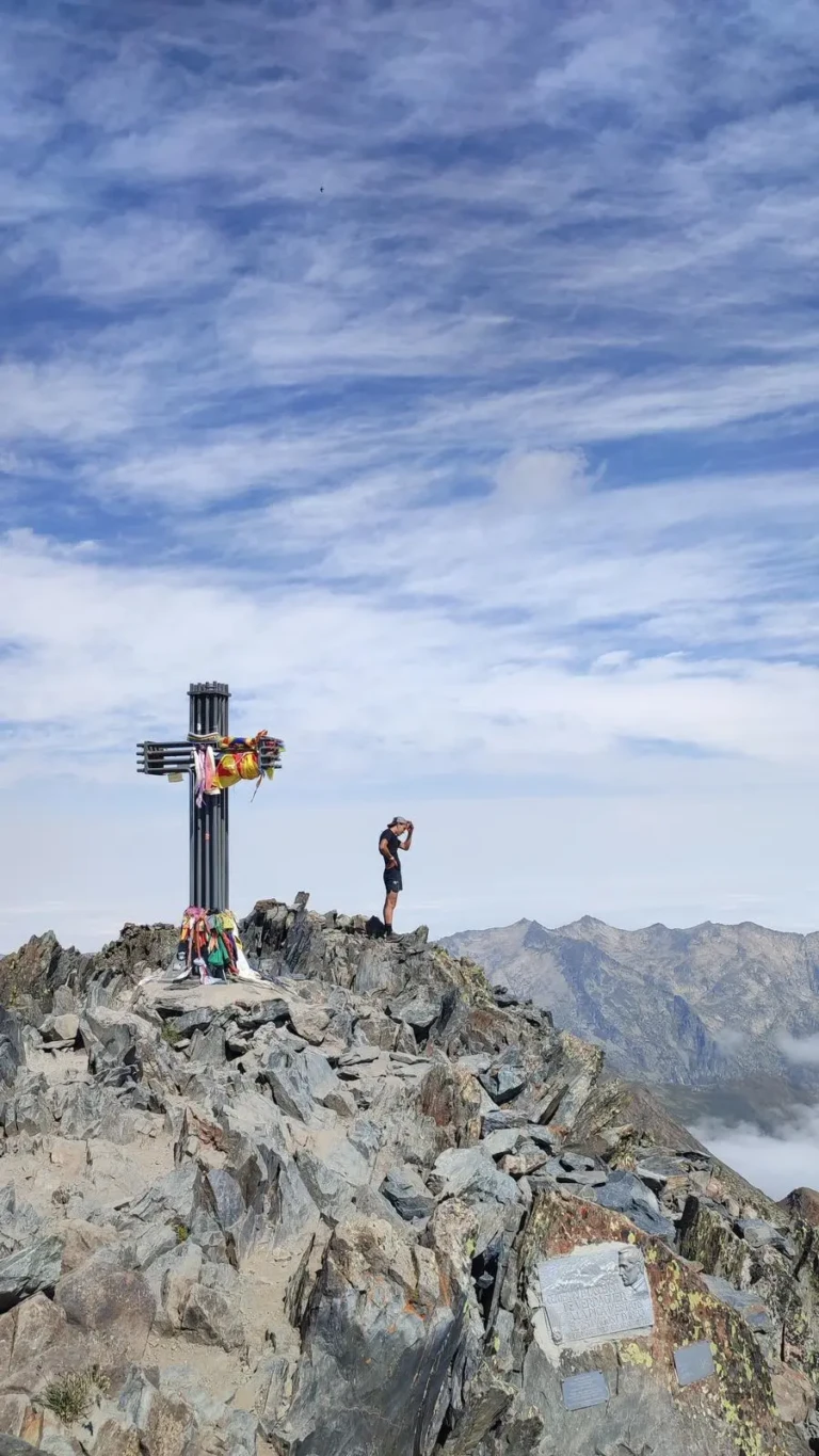 Un jove muntanyenc amb motxilla i botes de trekking observant les vistes panoràmiques del Pirineu des del cim de la Pica d'Estats.