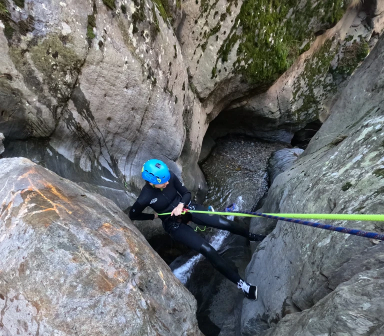 Deportista descendiendo con cuerda por una cascada en un barranco estrecho y frondoso cerca de Llavorsí.