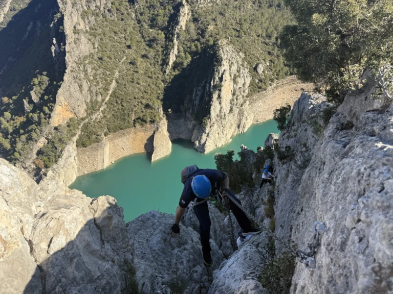 Un noi subjectant-se a una cadena de ferro per pujar un tram de roca inclinat en una via ferrada d'iniciació.