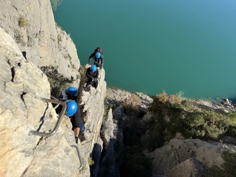 Un escalador progressant per l'estret fil d'una cresta de roca amb vistes aèries del paisatge.